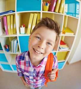 Smiling schoolboy with backpack ready for back to school looking at camera