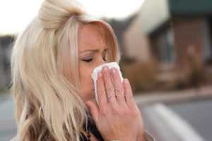 young woman sneezing into a tissue with really bad indoor allergies