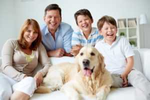 family with pet dog sitting on sofa after cleaning up after pet