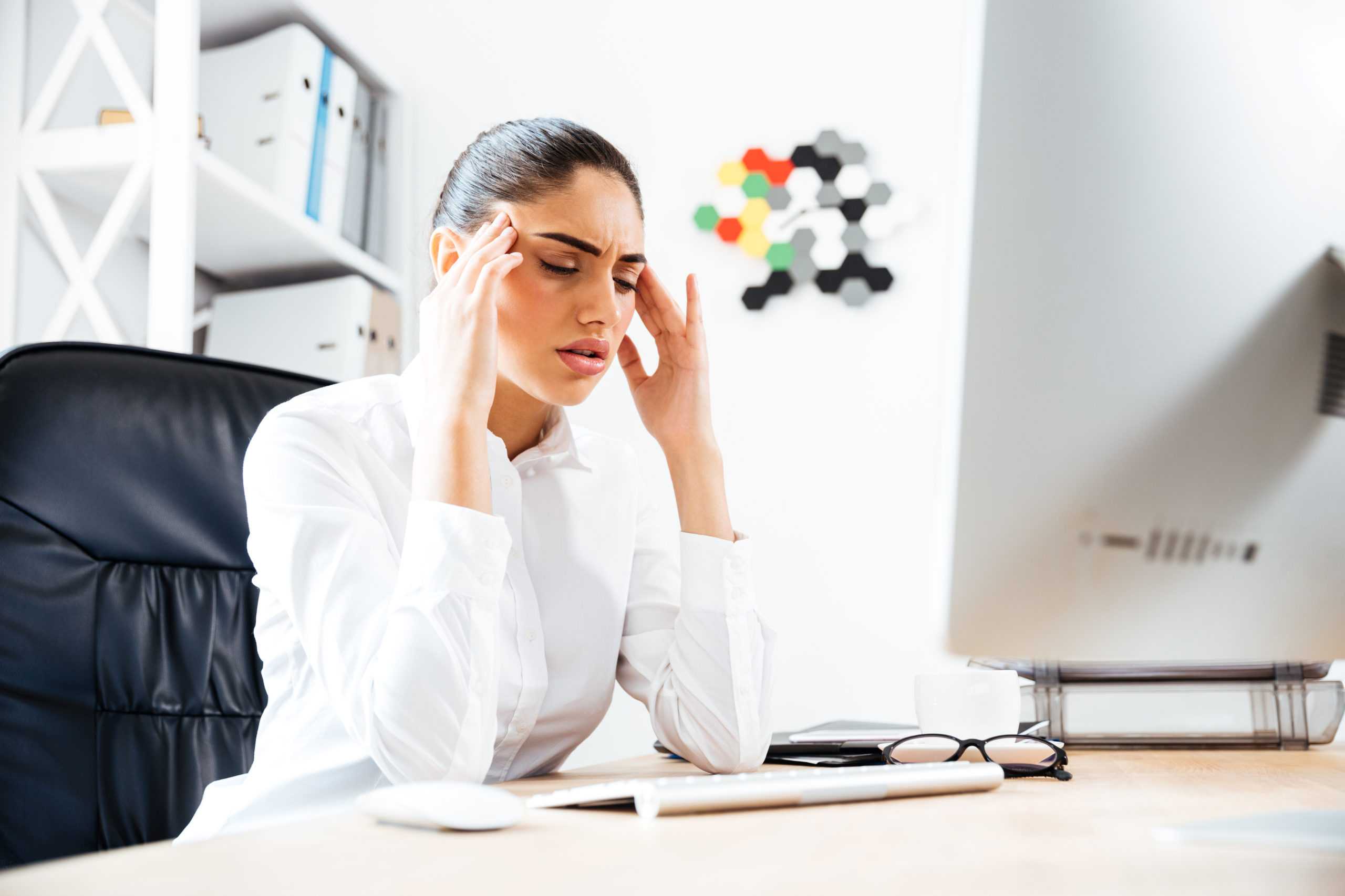 sick employee holding head at office