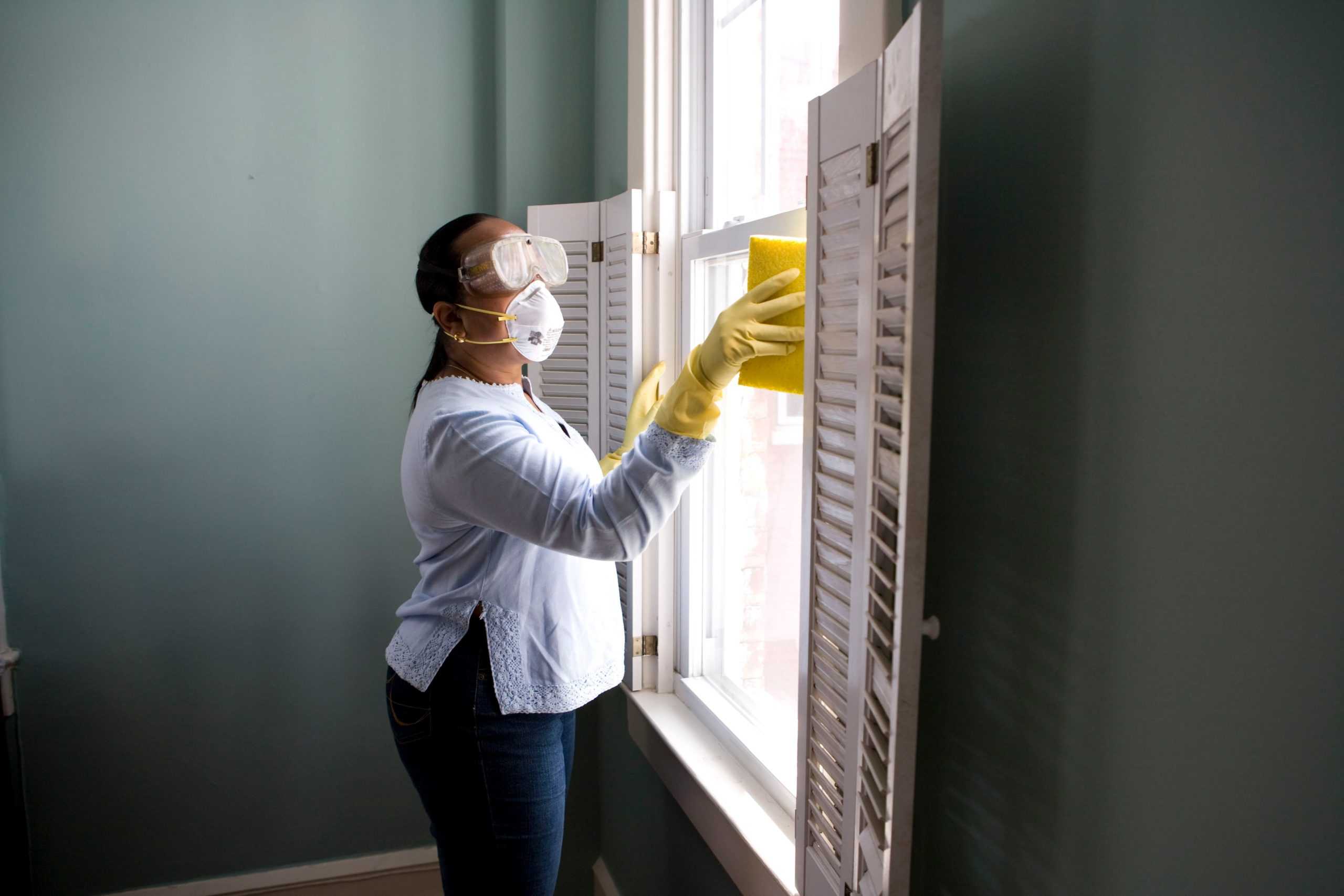 person cleaning with mask and using home cleaning tips for households with allergies